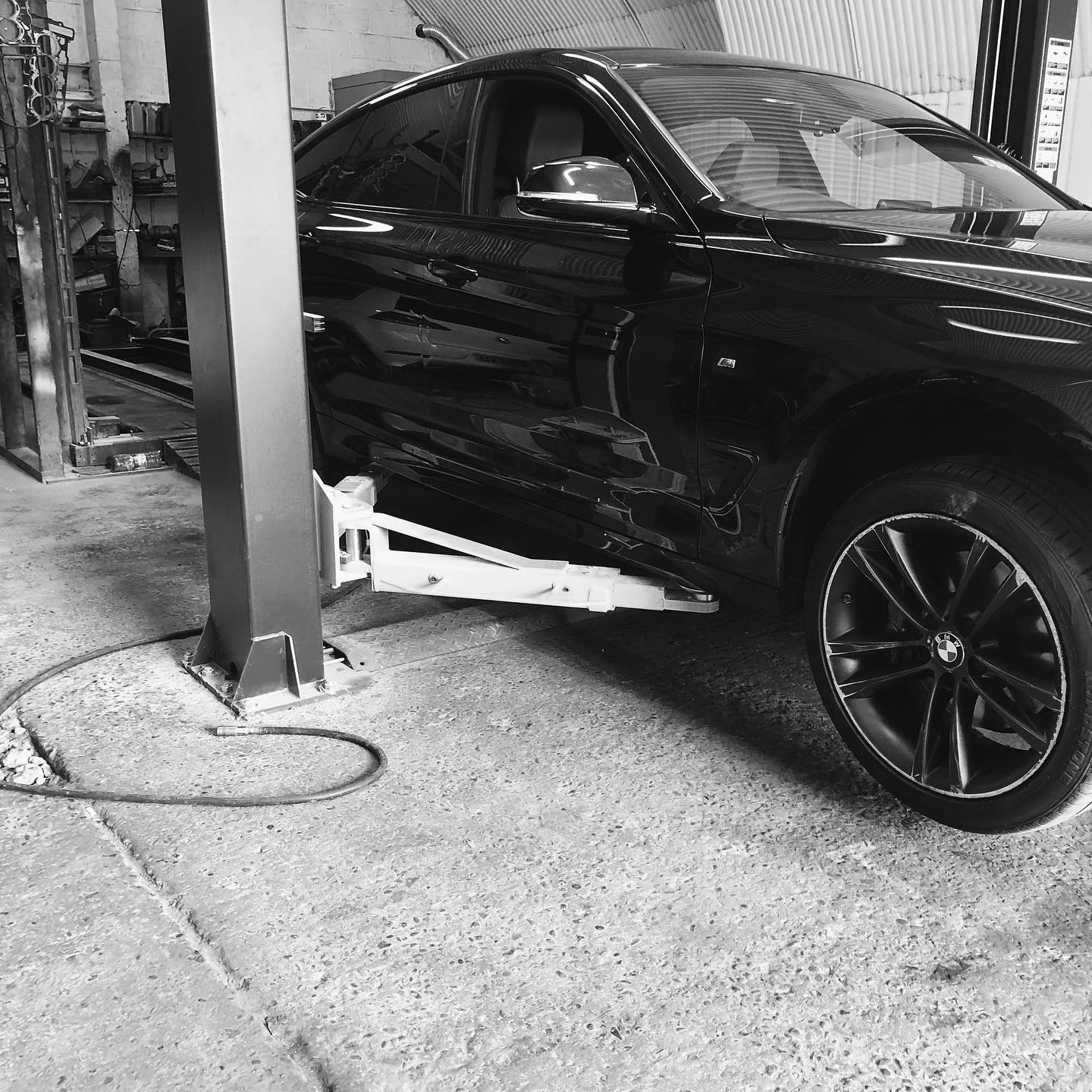 Black BMW raised on the two-post lift in the ADE Auto Repairs workshop