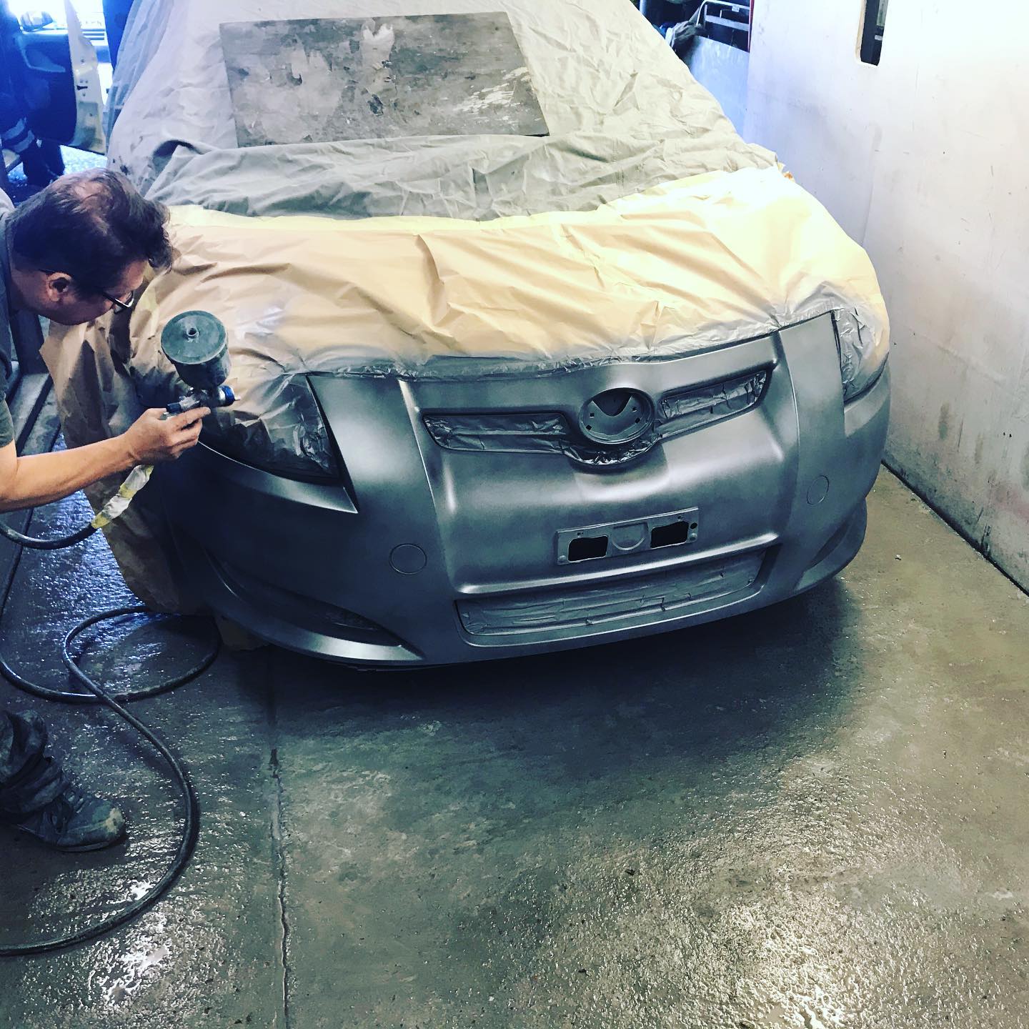 Mechanic spraying a Toyota front bumper in the ADE bodyshop spray booth